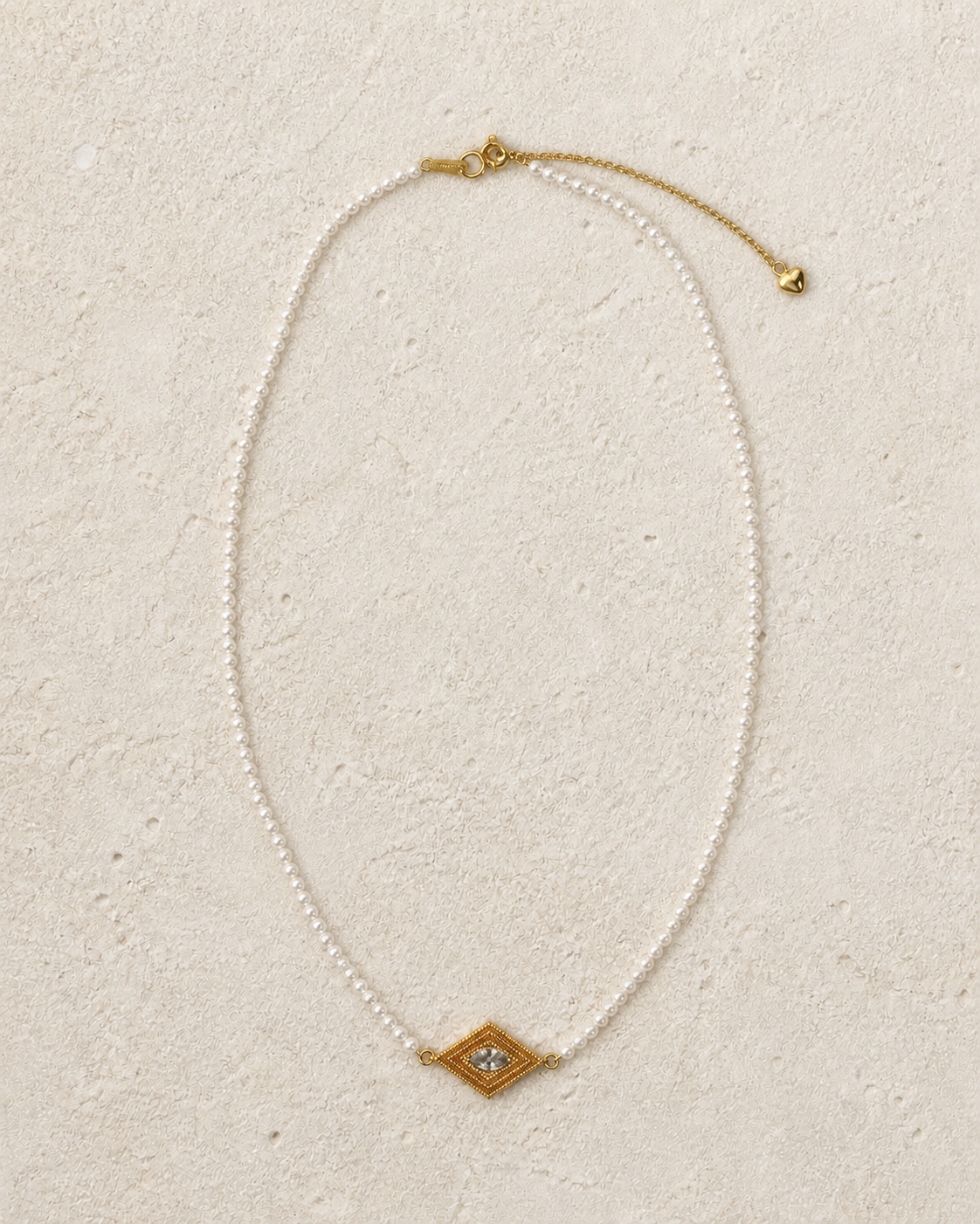 Delphi Pearl Eye Necklace arranged on warm ivory limestone