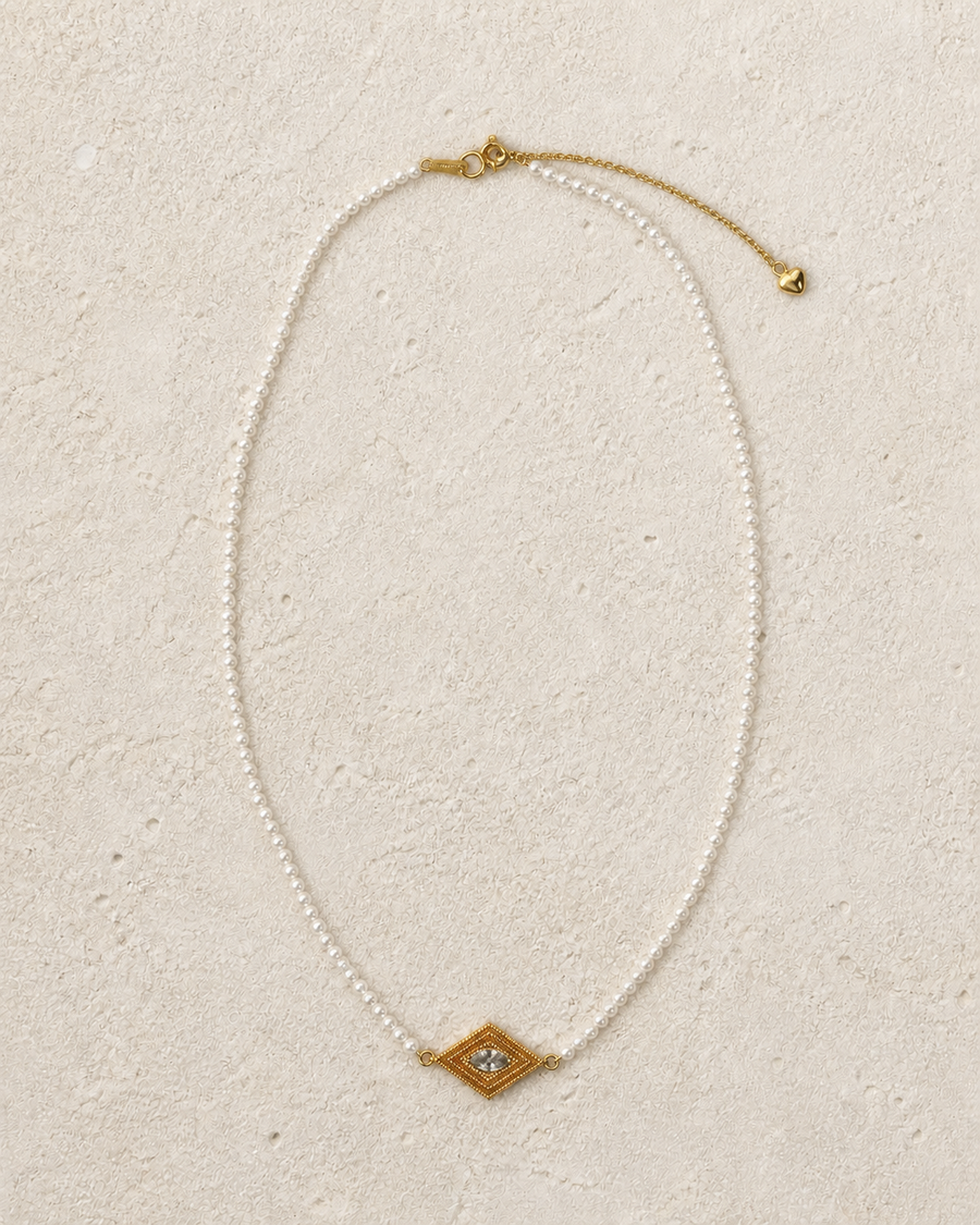 Delphi Pearl Eye Necklace arranged on warm ivory limestone