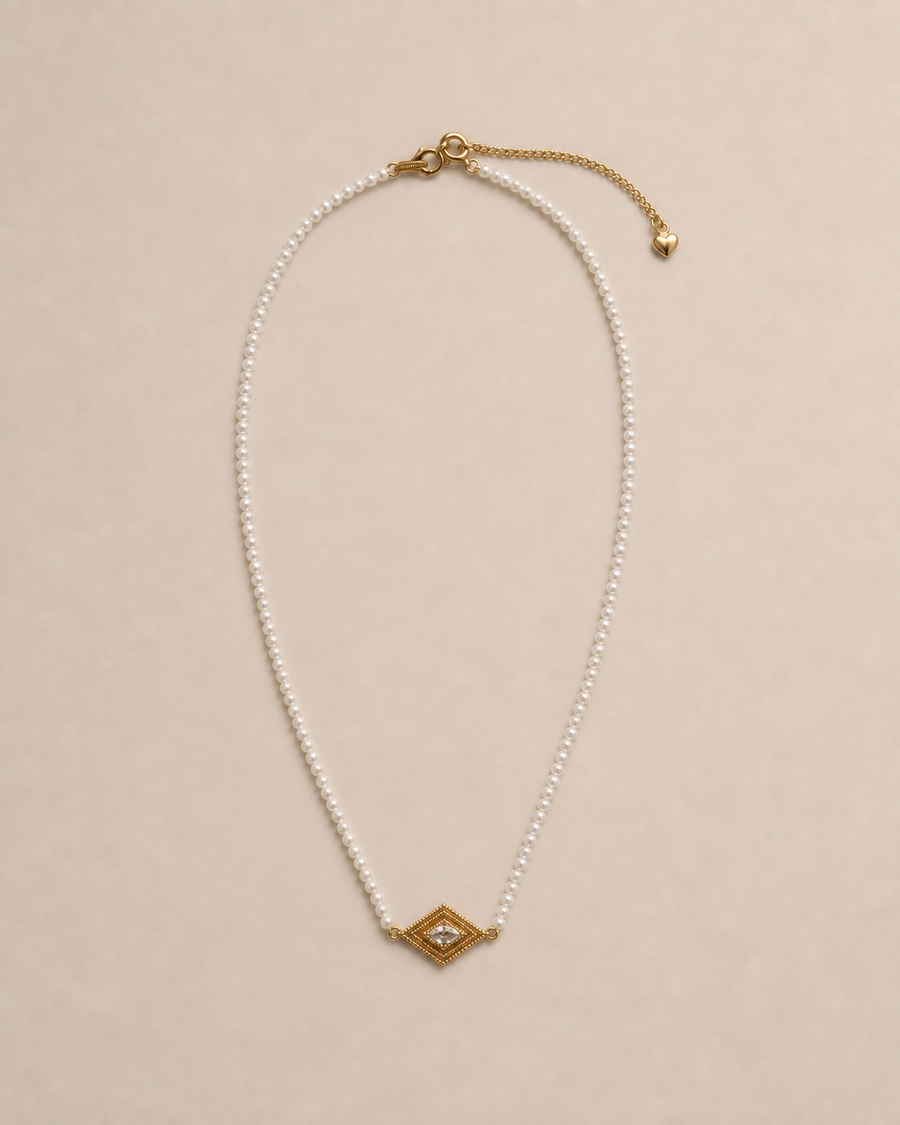 Delphi Pearl Eye Necklace in a warm neutral studio setting