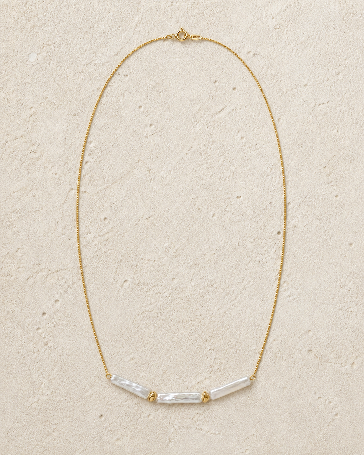 Linea baroque pearl necklace laid on warm ivory limestone