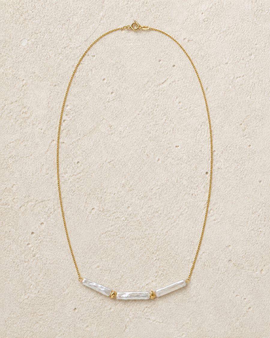 Linea baroque pearl necklace laid on warm ivory limestone