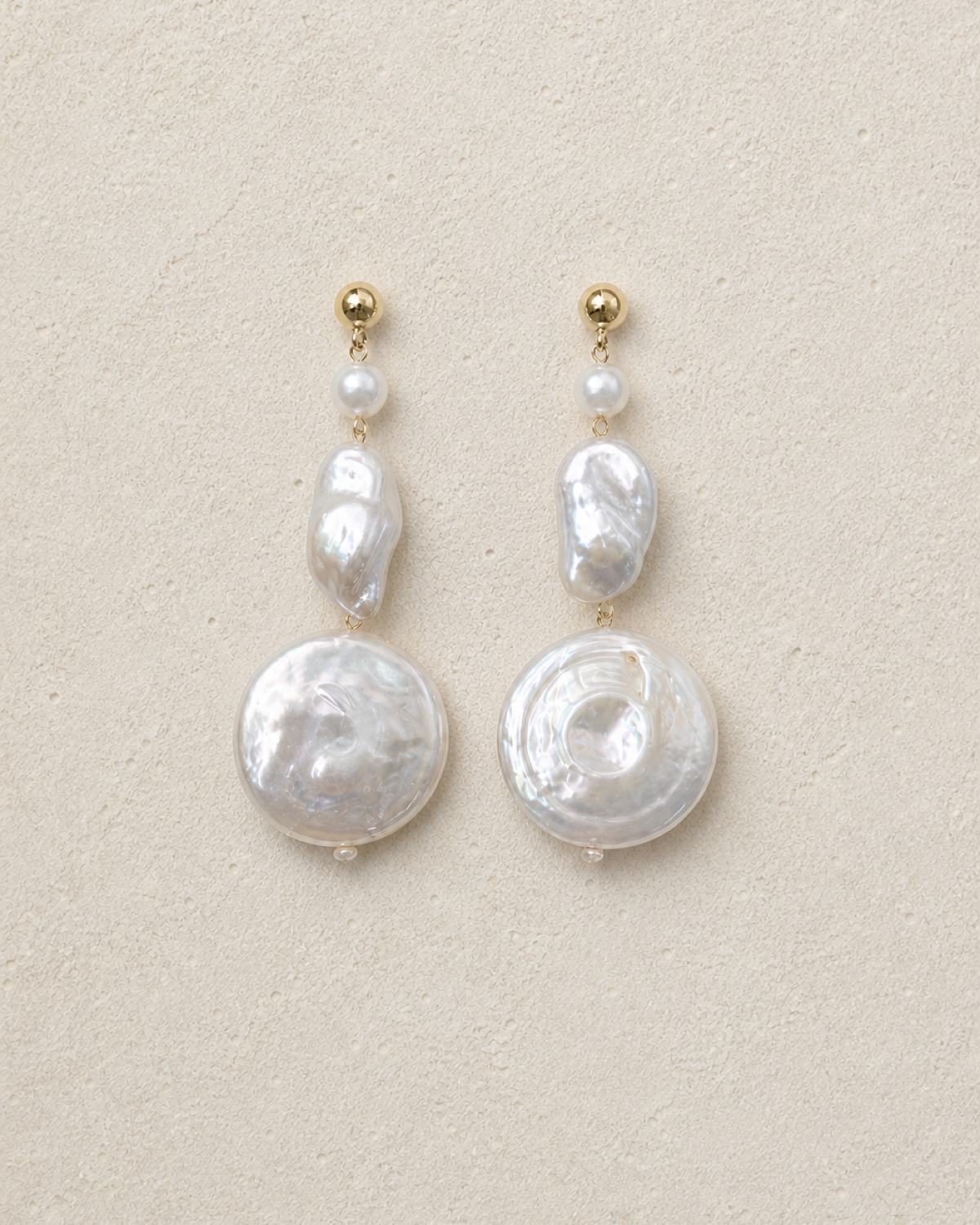 Luna Coin Pearl Drops laid on warm ivory limestone
