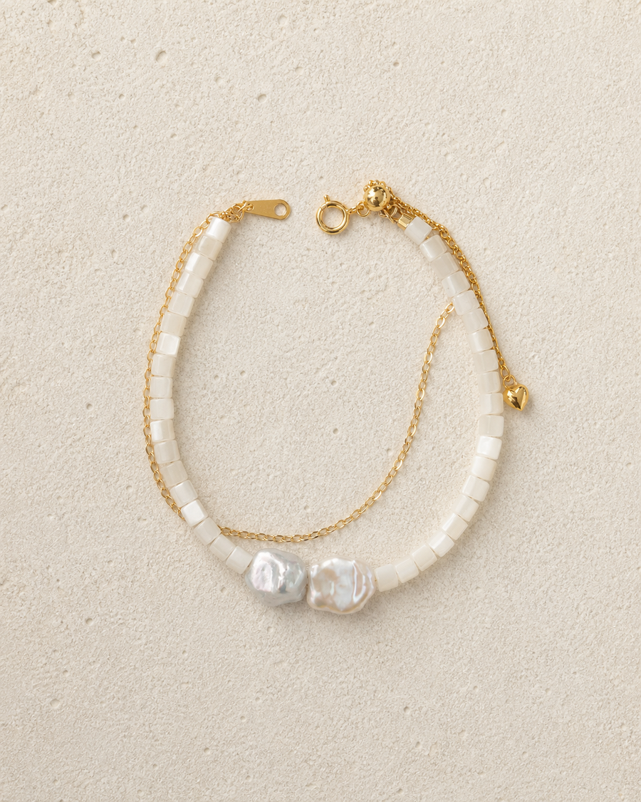 Tide Double-Strand Pearl Bracelet resting on warm ivory stone