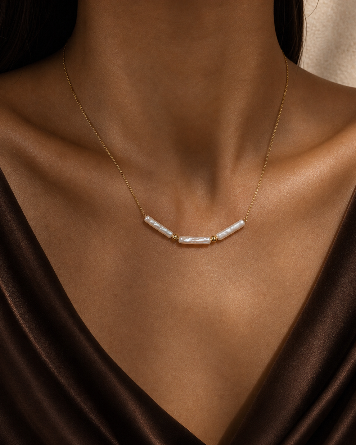 Linea Baroque Pearl Necklace worn at the collarbone in a warm bronze and espresso editorial close-up