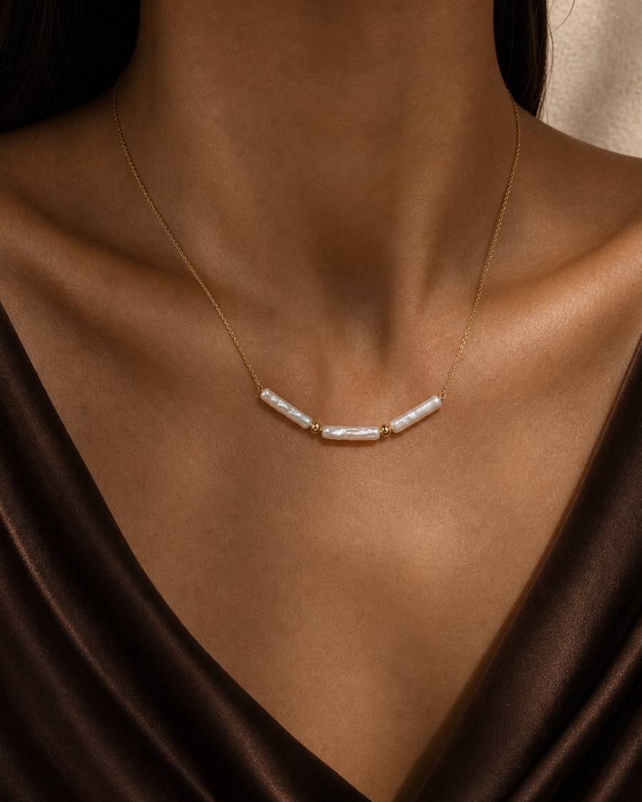 Linea Baroque Pearl Necklace worn at the collarbone in a warm bronze and espresso editorial close-up