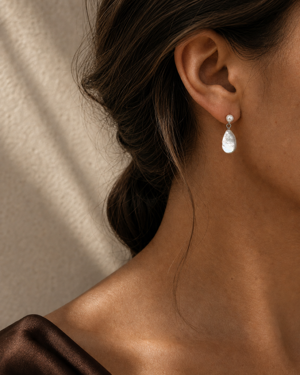 Lumen Teardrop Pearl Earring worn in a warm bronze and espresso editorial close-up